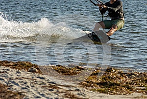 Expert Kitesurfer Planing close to the beach with Pictoresque Sea Watrer Splashes at sunset