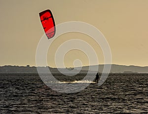 Expert Kitesurfer Planing with  Sea Watrer Splashes during Golden Hour