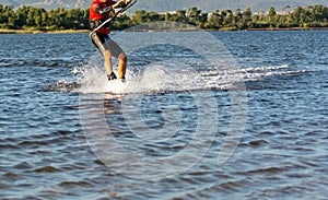 Expert Kitesurfer Planing with  Sea Watrer Splashes during Golden Hour on Blurred Background