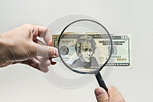 Expert with magnifying glass checks suspicious money. search watermarks on paper of the fake bills. magnifying glass, magnifier, m