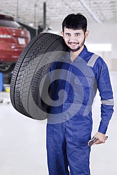 Expert mechanic carrying a tire in workshop
