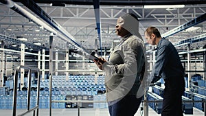 IT expert monitors server farm activity while walking on industrial platform