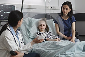 Expert pediatrician prescribing medication for little girl disease resting in patient bed