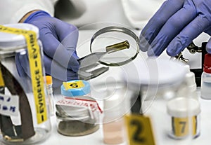 Expert police examines a bullet cap in scientific laboratory with magnifying glass