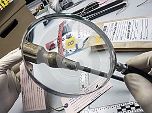 Expert police examines with magnifying glass a screwdriver in laboratory forensic equipment