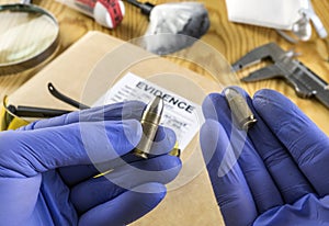 Expert police officer comparing two nine millimeters bullets in ballistics laboratory photo