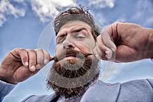 Expert tips for growing and maintaining moustache. Man bearded hipster twisting mustache sky background. Ultimate