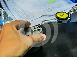 An expert is using a high-gauge tool to check the scale of the workpiece. for accuracy to meet quality standards