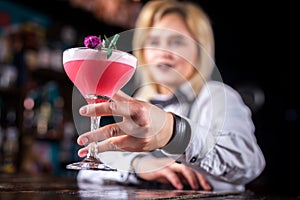 Expert woman bartender demonstrates his skills over the counter in the nightclub
