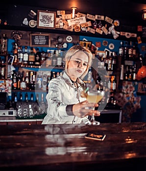 Expert woman bartender pouring fresh alcoholic drink into the glasses at the night club