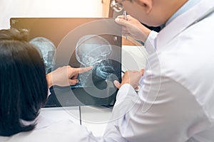 Expertise doctor planning treatment for medical concept. Two asian doctor looking at film x-ray head of patient and discussing