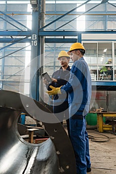 Experts checking information on tablet PC in a modern factory