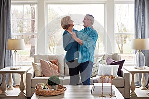 The experts in romance. a happy mature couple dancing together in their living room at home.