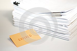 Expired; Stack of Documents on white desk and Background.
