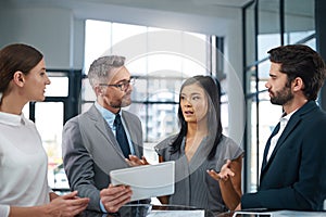 Explaining her theory. a group of businesspeople looking over a digital tablet in the office.