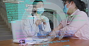 Explaining white-lab-coat doctor holding model at table, masked patient in pink-shirt, code overlay