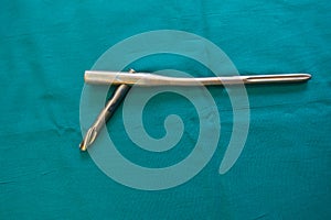 An explanted femoral nail lie spread out on a green surgical drape