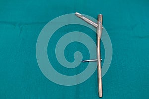 explanted femoral nail with locking screw lies on a green surgical drape