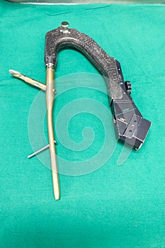 explanted femoral nail with locking screw lies on a green surgical drape