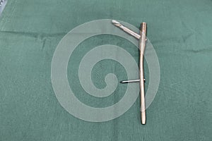 explanted femoral nail with locking screw lies on a green surgical drape