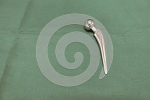 explanted femoral prosthesis lies on a green surgical drape