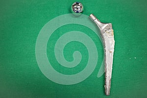 Explanted hip prosthesis was cleaned and lies on a green surgical drape