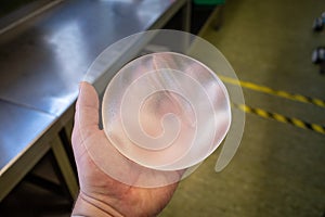 The explanted silicone breast implant lies in one hand