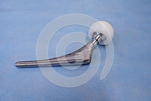 An explanted surgical hip prosthesis lies on an operating table