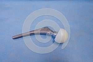 An explanted surgical hip prosthesis lies on an operating table