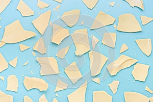 Exploded white chocolate Easter eggs over blue background, holiday