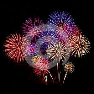 Exploding fireworks illuminate the night sky with vibrant colors, forming intricate