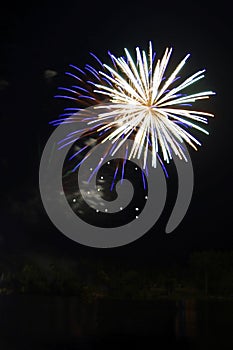 Exploding round white and blue fireworks in black night sky with copy space