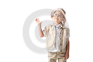Explorer boy in hat and glasses looking at camera and waving hand isolated on white