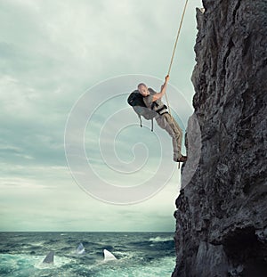 Explorer climbs a mountain with the risk to fall on the sea with sharks