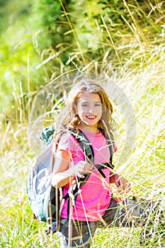 Explorer kid girl walking with backpack in grass