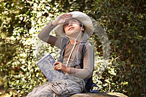 Explorer in the making. A little boy sitting with a book looking up at the sky.