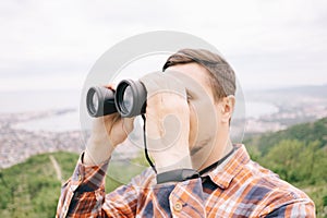 Explorer man looking through binoculars outdoor.