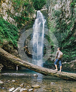 Explorer man looking at waterfall.