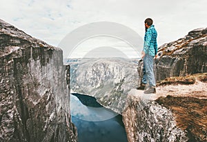 Explorer man standing on cliff over fjord solo traveling