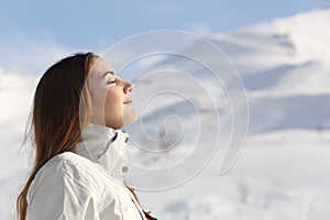 Explorer woman breathing fresh air in winter in a snowy mountain photo