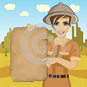 Explorer woman with safari hat holding treasure map in desert