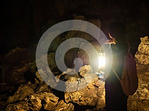 Explorer woman standing with an oil lamp Use bright lights to travel through very dark and natural stalagmite and rocky caves