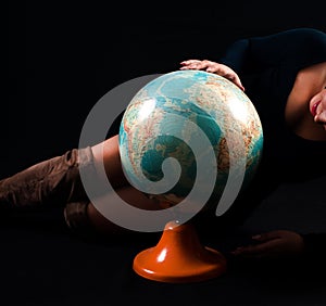 Exploring Beauty: Curvaceous Woman Engaging with a Grand Globe in Studio Setting