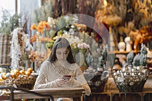 Exploring the decor shop, a young woman holds a phone in her hands.