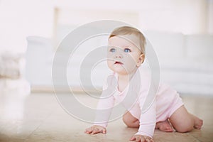 Exploring the floor- baby crawling. Shot of a little baby girl crawling on the floor indoors.