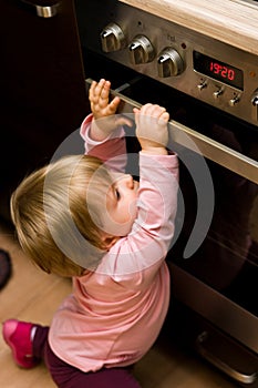 Toddler gripping kitchen oven door photo