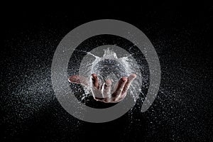 Explosion of a balloon full of water held on a hand, black background studio shot