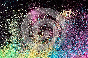An explosion of colorful pigment powder on black background. Vibrant color dust particles textured background
