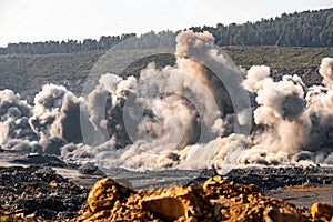 Explosive works on open pit coal mine industry with dust and puffs of smoke