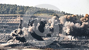 Explosive works on open pit coal mine industry. Dust and puffs of smoke in sky, blasted soil